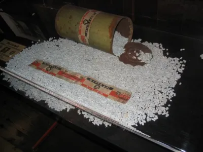 Eine ausgekippte liegende Dose mit Zyklon B. Das weiße Granulat, welches das Gift enthielt, ist um die Dose ausgebreitet.
