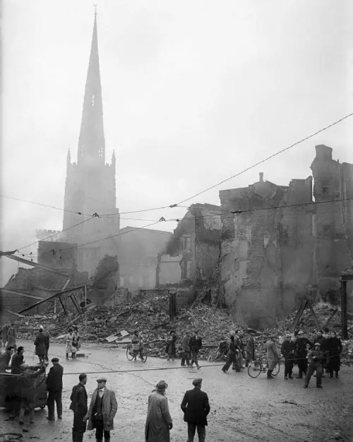 Zertrümmerte Häuser in Coventry, auf der Straße davor gehen Menschen.