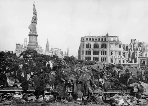 Trümmer und zerstörte Häuser, im Vordergrund ein Berg von Leichen nach den alliierten Bombenangriffen.