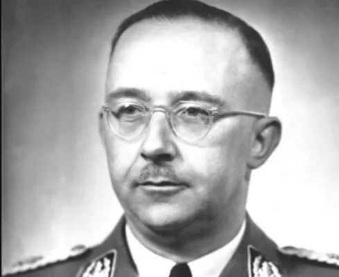 Schwarzweiß-Porträt: Heinrich Himmler mit kurzem Haarschnitt, Brille und Bartschatten auf der Oberlippe, trägt eine Uniform mit Abzeichen.