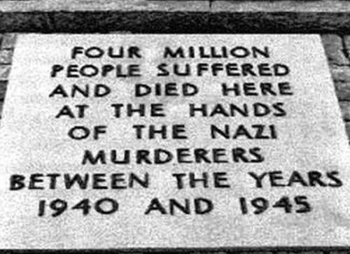 Foto der alten Gedenktafel in Auschwitz, schwarze Schrift, Großbuchstaben in englischer Sprache auf grauem Untergrund. Transkription folgt unten.